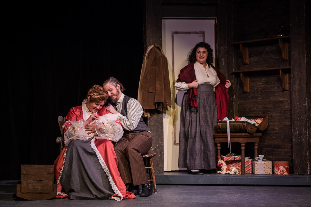  From left to right, Anne Cratchit (Hannah Rockel) and Bob Cratchit (Jaron Boggs) celebrate the birth of their baby while friend and co-worker Agnes (Jessica Robins) looks on. Photo by Michael Brunk. 