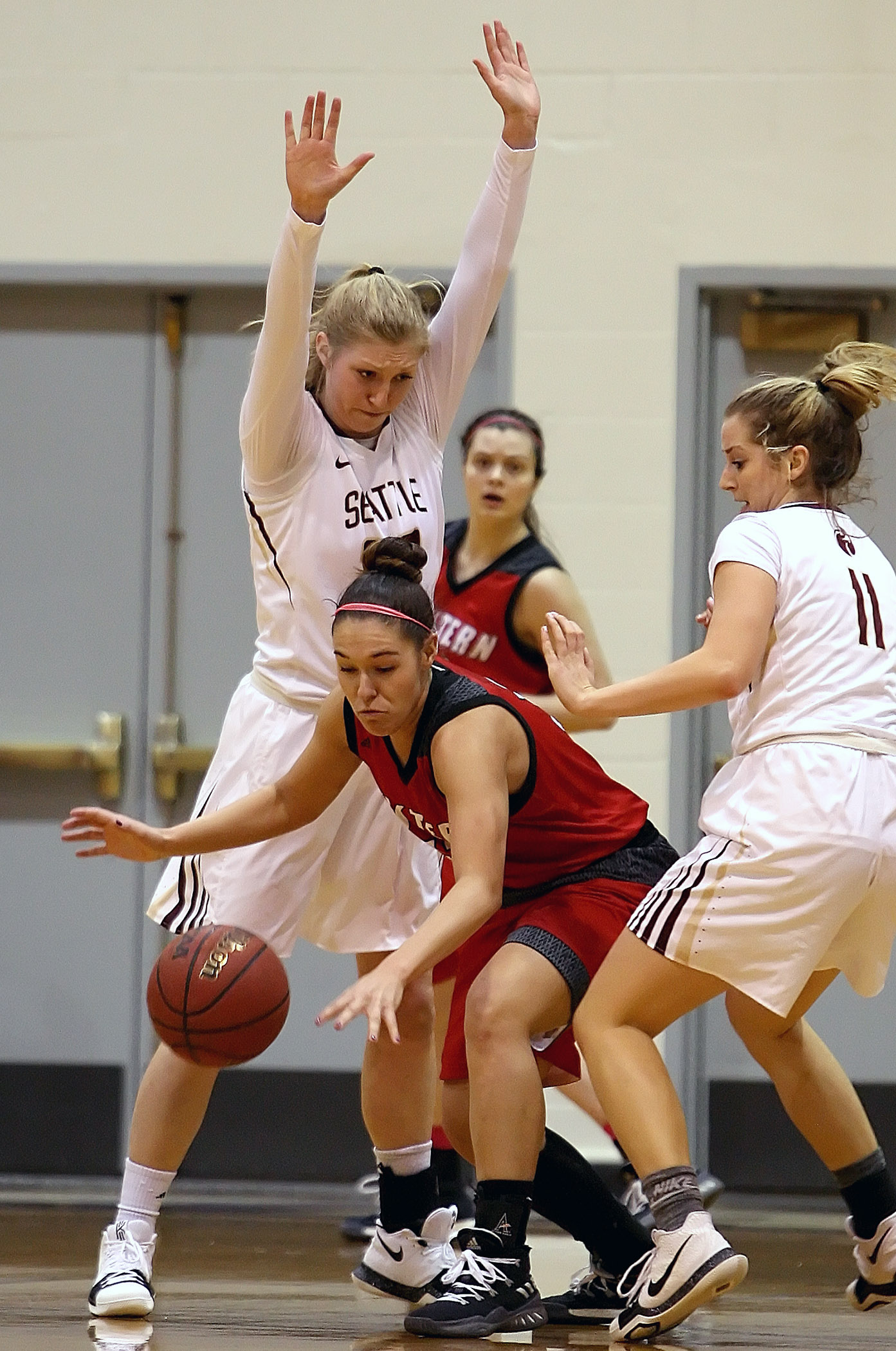 Sydney Azorr of Western Oregon gets sandwiched between Seattle Pacific’s Erica Pagano and Jaylee Albert.