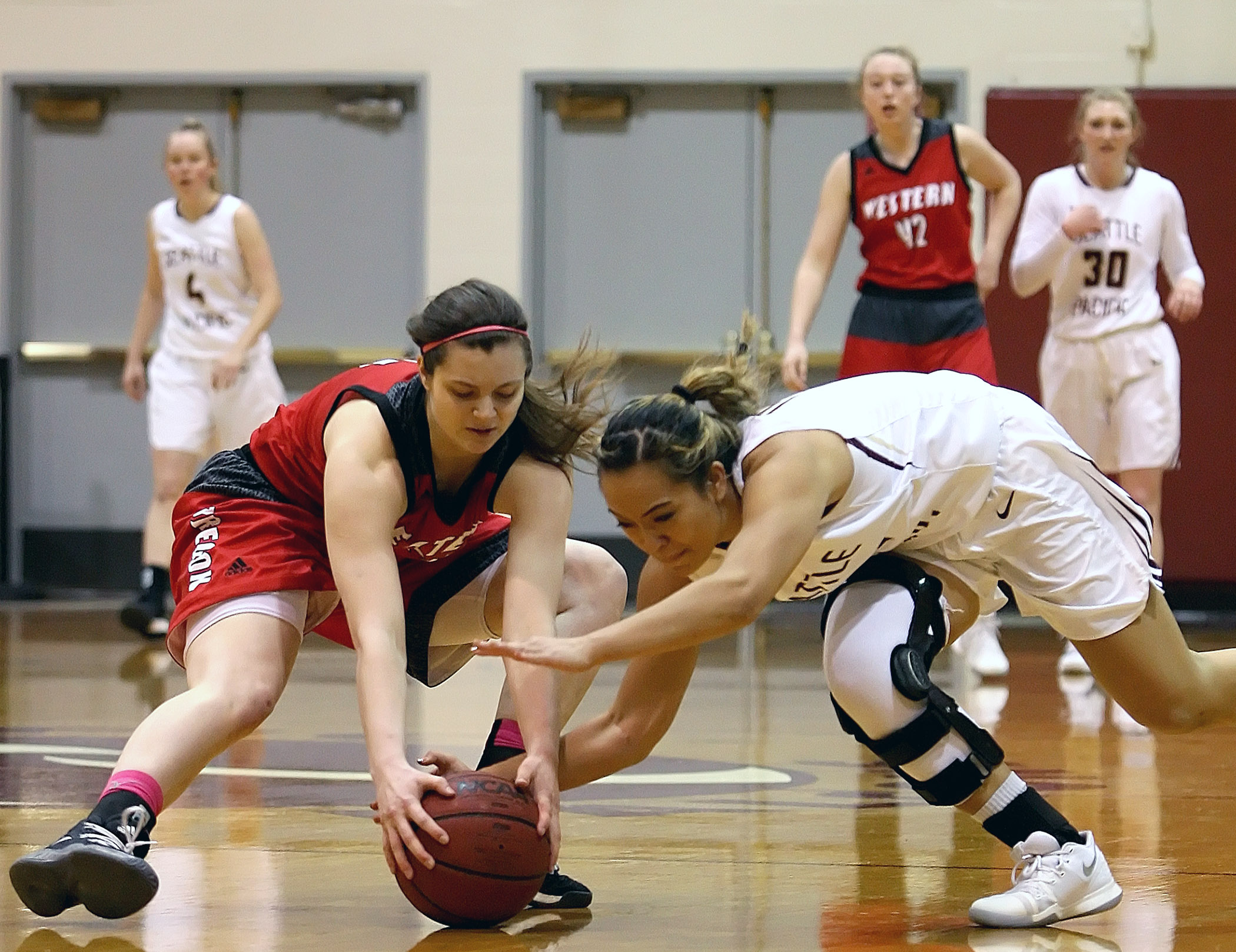 Savannah Heugly of Western Oregon and Seattle Pacific’s Rachel Shim try to get control of the ball.
