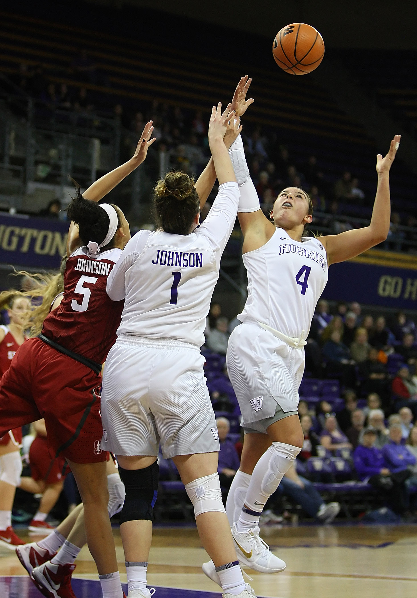 Amber Melgoza of Washington pulls down a rebound as Stanford’s Kaylee Johnson and Washington’s Hanna Johnson watch.