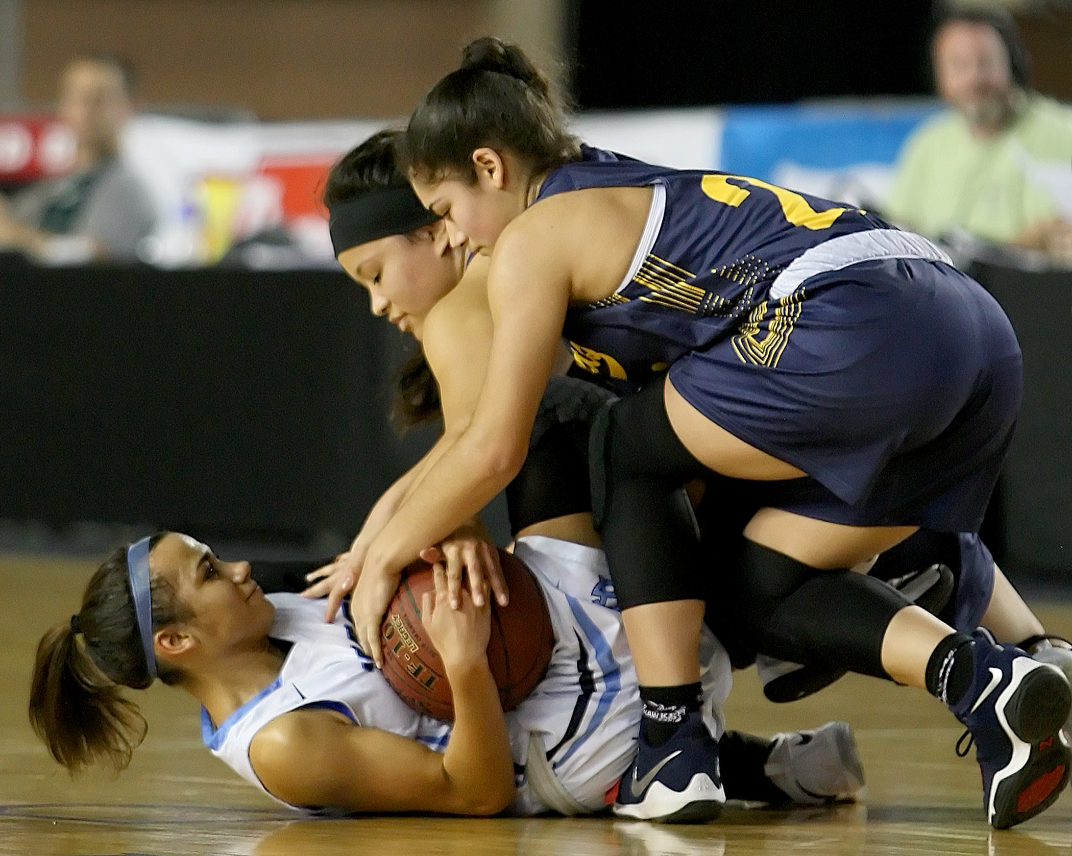 Sydney Langworthy of Gig Harbor lays on her back clutching the ball as Jasmine Gayles and Juliana Horne try to take it away.