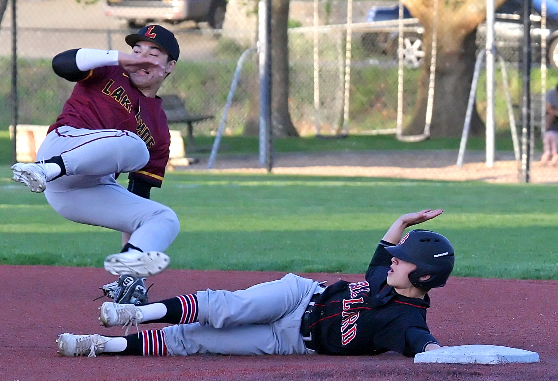 Jake Korman of Lakeside falls backwards as Ballard's Peter Furia safely gets back to second base.