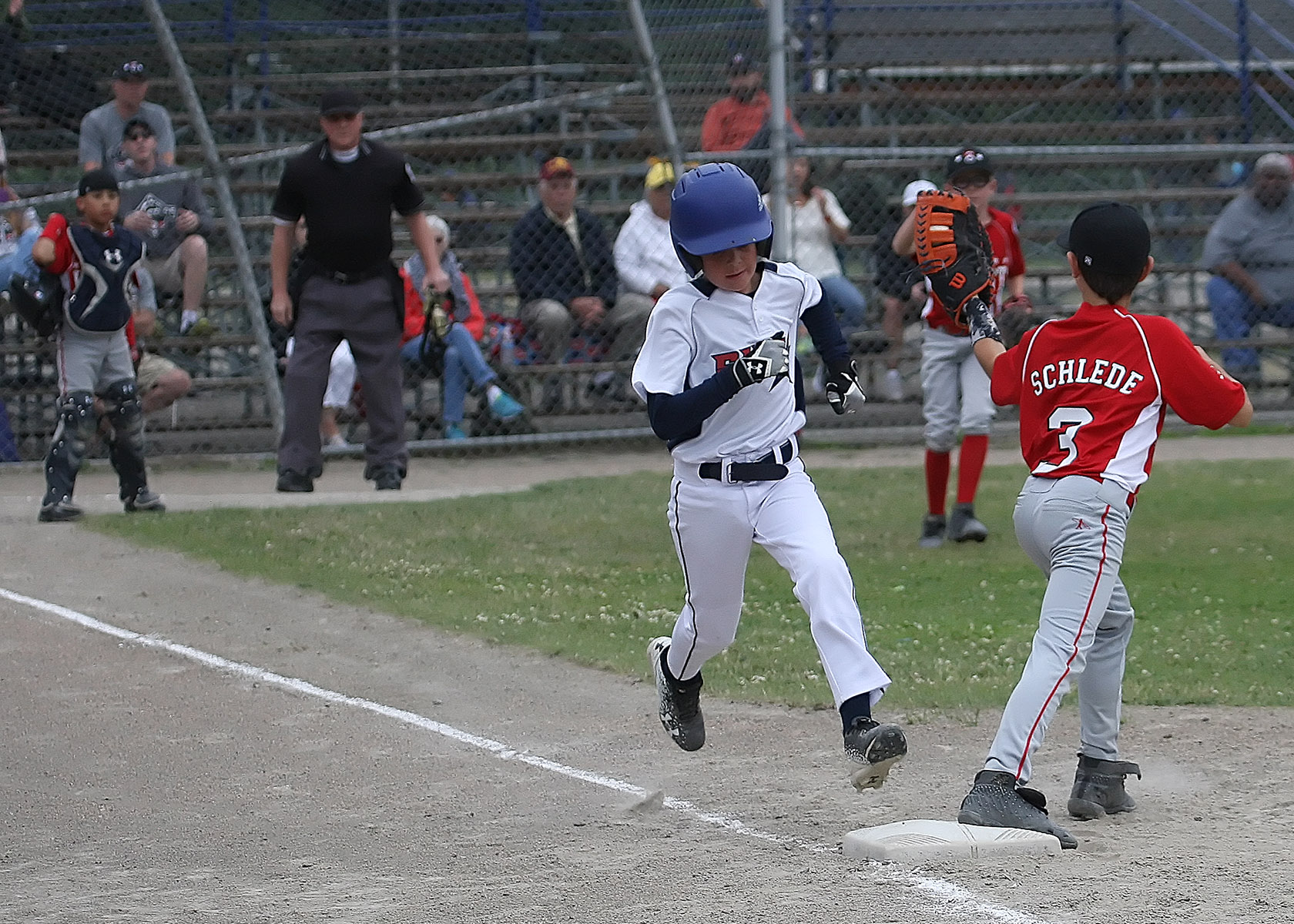 Ryan Keane of South Highline Nationals is out at 1st as West Seattles Otis Schlede catches the ball.