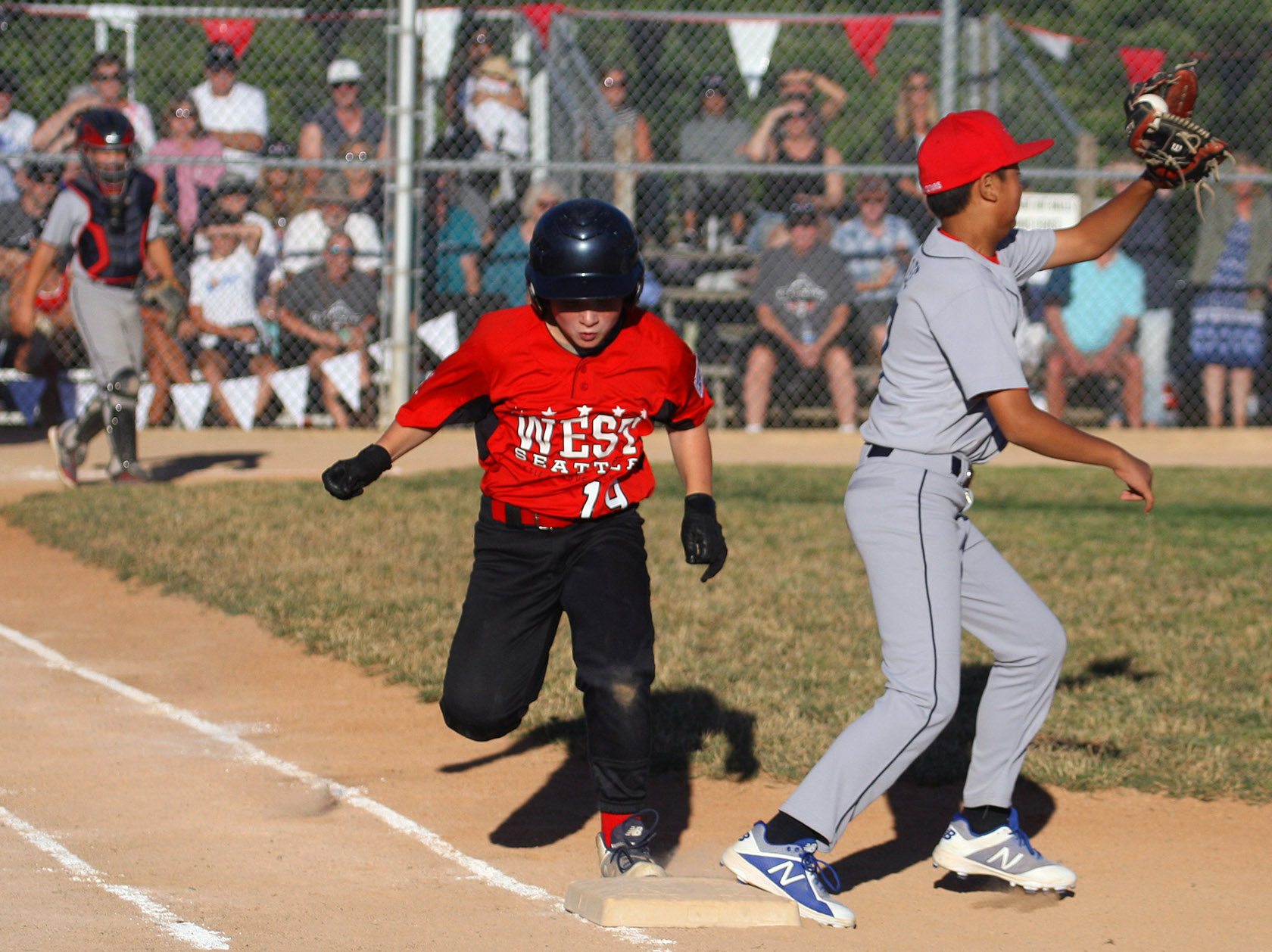 Bobby Trigg of West Seattle is safe at first as Renton's first baseman Maurie Solam catches the ball.