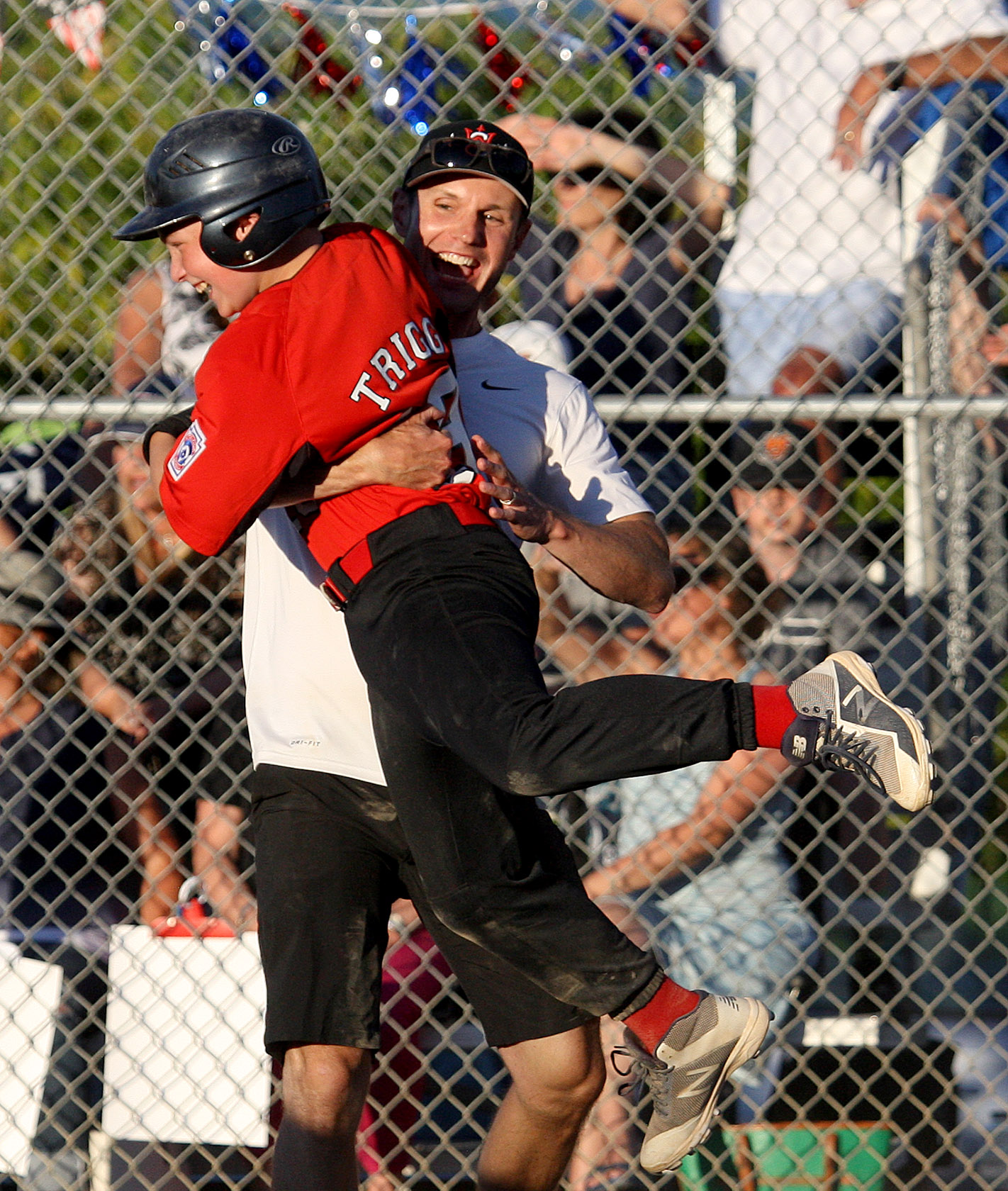 Bobby Trigg of West Seattle gets a lift from his coach after scoring the game winning run.